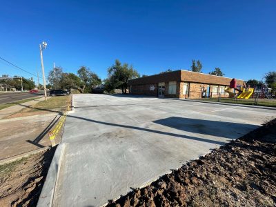A construction site showing a parking lot being built for the new school, with machinery and materials visible.