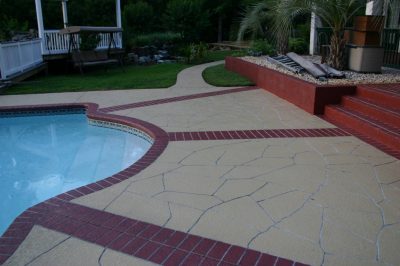 A swimming pool surrounded by a red brick patio and steps leading into the water.