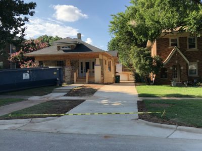 A house surrounded by a fence, marked with yellow caution tape indicating a potential hazard or restricted area.