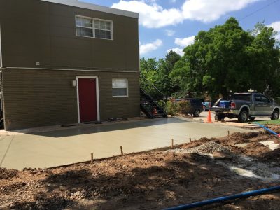 Concrete driveway construction underway in Dallas, Texas, showcasing workers and equipment on-site.