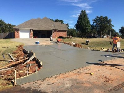 Concrete driveway construction underway in Oklahoma, showcasing workers and equipment on a residential site.