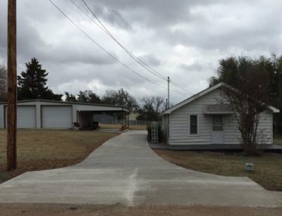 A residential house with a paved driveway and an attached garage, set in a suburban neighborhood.