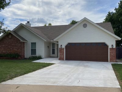 A house featuring a garage and a paved driveway, set in a residential neighborhood.