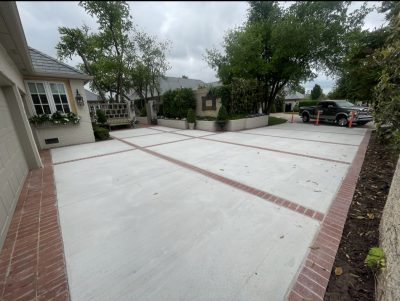 A driveway featuring a brick walkway and a matching brick sidewalk alongside it.
