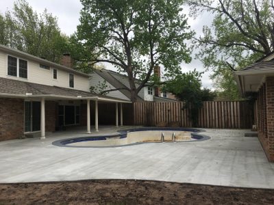 A backyard pool surrounded by a wooden fence, providing a private and inviting outdoor space for relaxation.