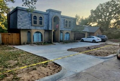 A house surrounded by yellow tape, indicating a restricted area or ongoing investigation.
